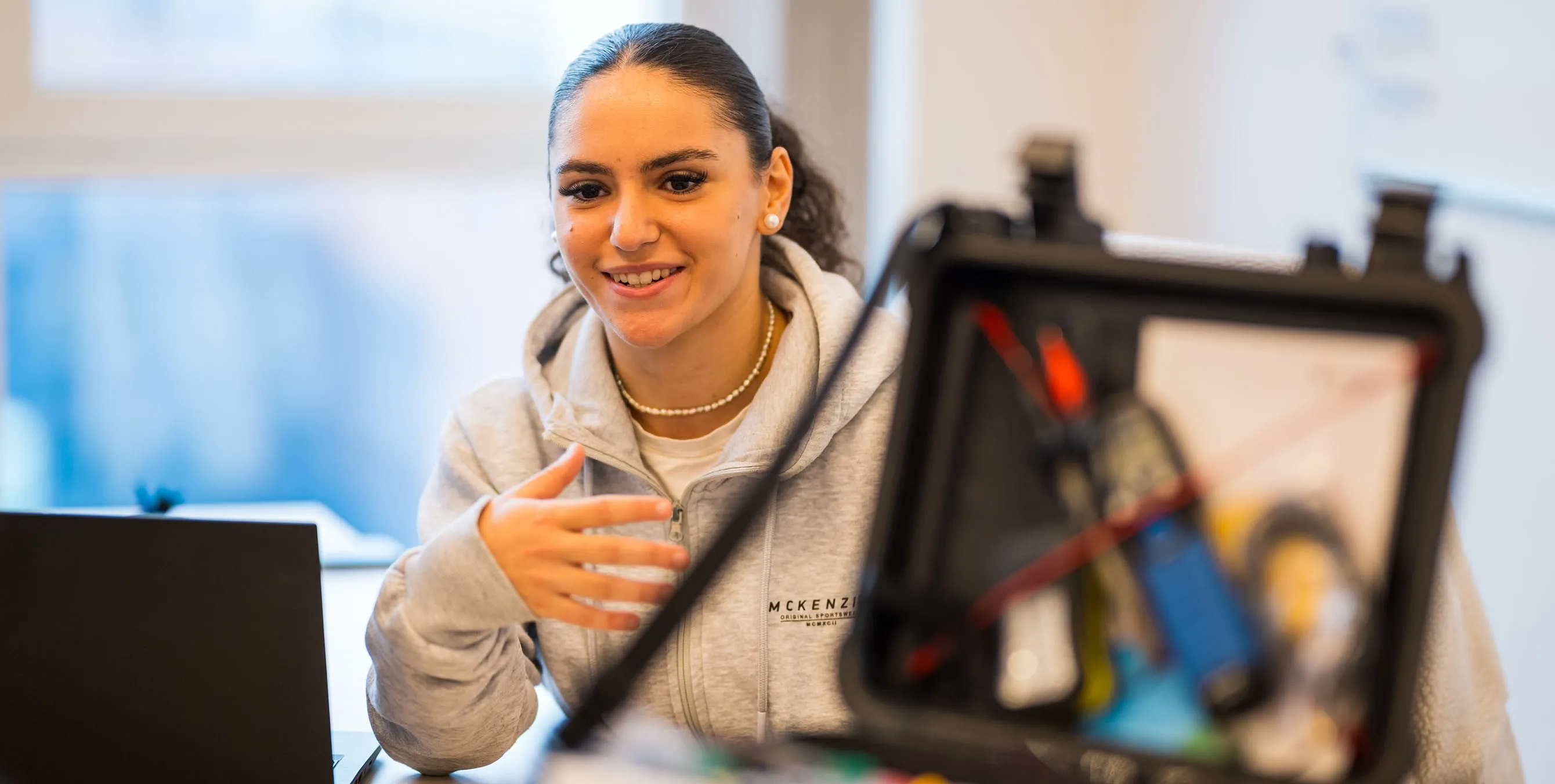 Eine junge Frau hinter einem geöffneten Werkzeugkasten. Sie lächelt und erzählt etwas. Foto: City-Press GmbH