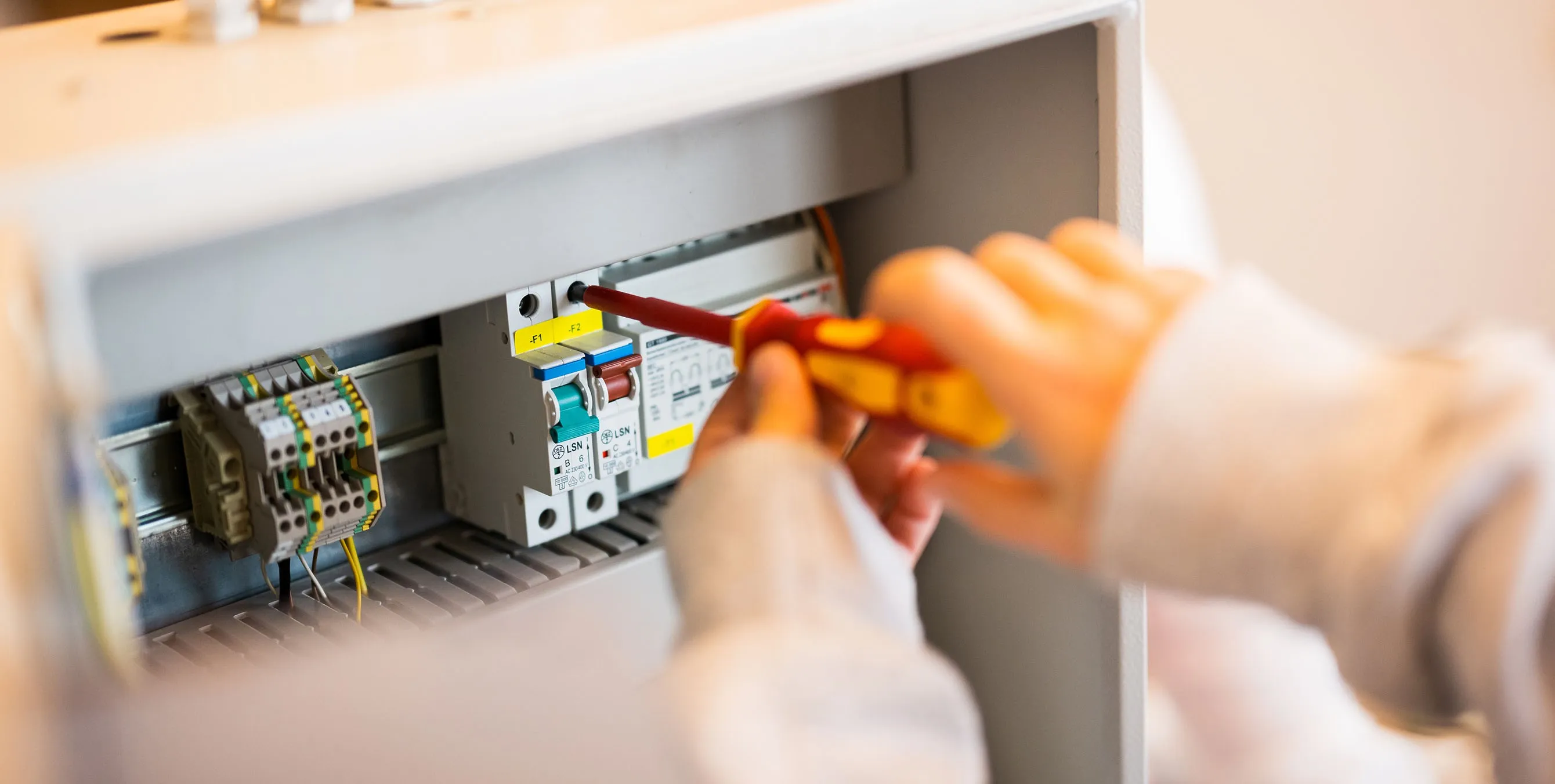 Großaufnahme: Zwei Hände halten einen Schraubendreher und befestigen ein Element in einem Schaltkasten. Foto: City-Press GmbH