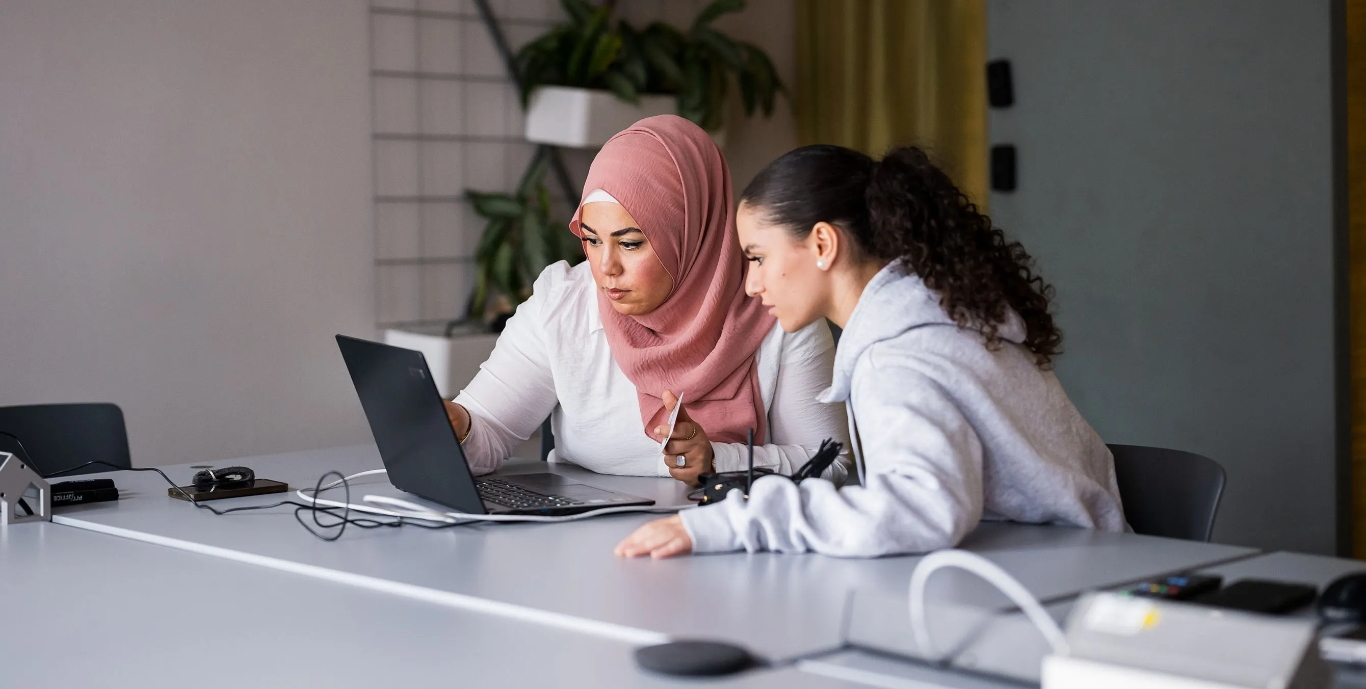Zwei Frauen sitzen nebeneinander vor einem Laptop und schauen sich konzentriert etwas auf dem Bildschirm an. Foto: City-Press GmbH