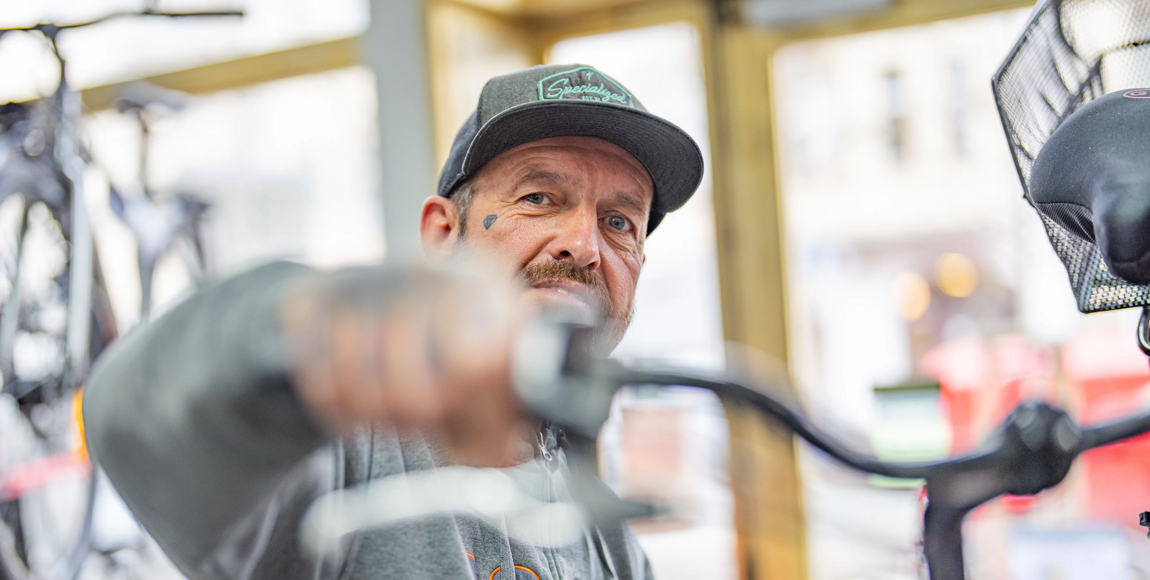 Mitarbeiter der Radwelt Berlin Pankow hält ein City-Bike am Lenker und schaut dabei in die Kamera.