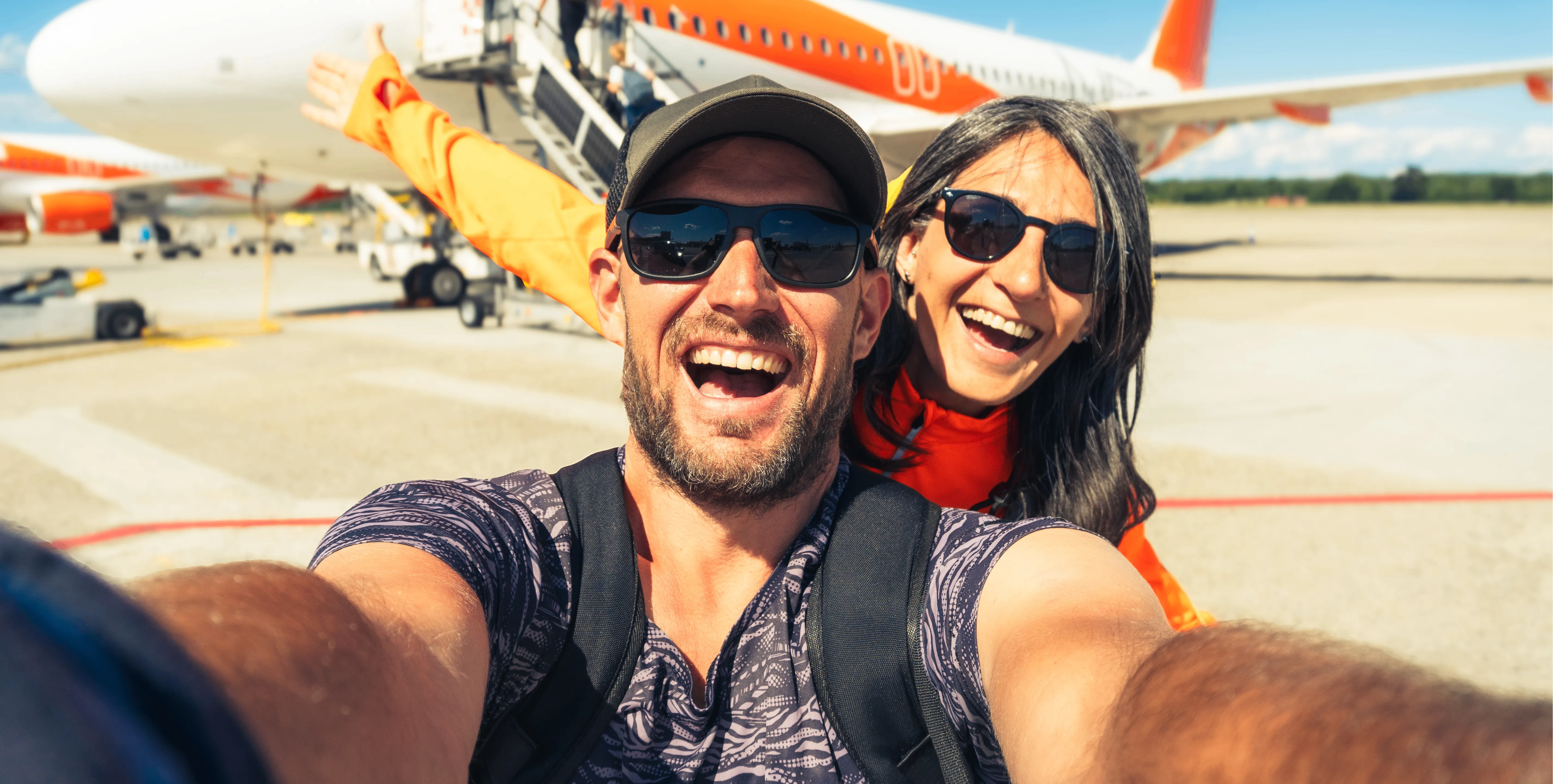 Ein verliebtes Pärchen macht ein Selfie vor dem Einsteigen in den Urlaubsflieger.