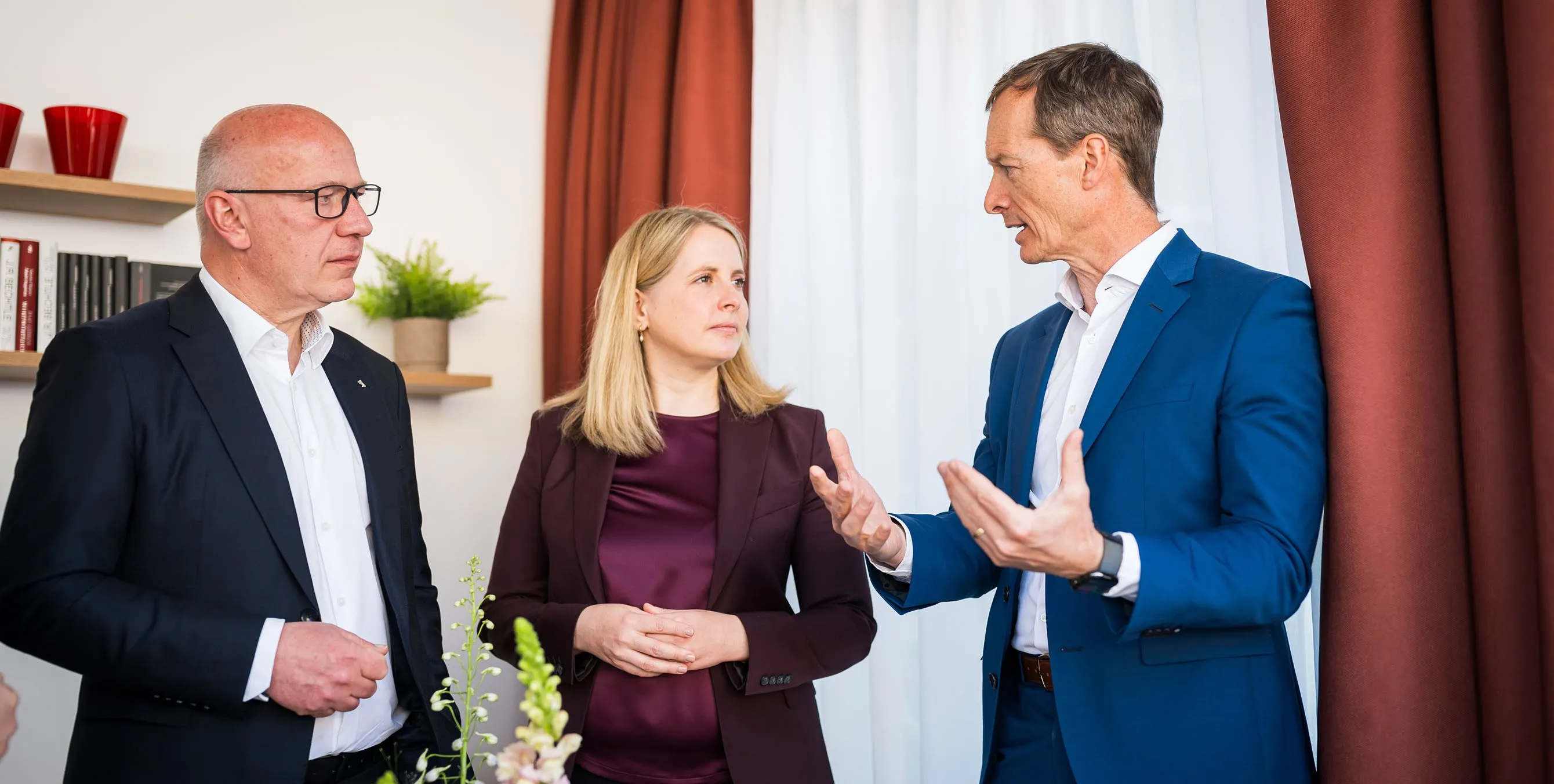 Zwei Männer und eine Frau stehen in einer Wohnung und diskutieren miteinander. Foto: City-Press GmbH