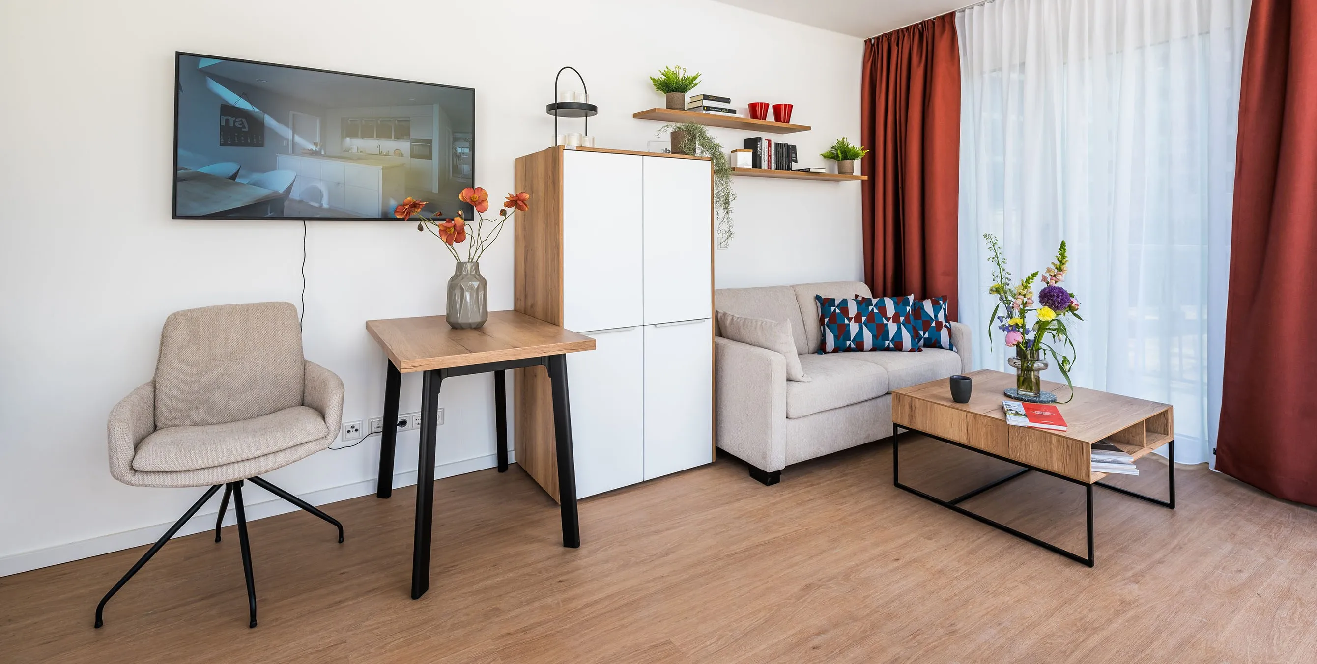 Einblick in eine eingerichtete Wohnung mit Sofa, Schrank, kleinen Tischen, Fernseher und Vorhängen. Foto: City-Press GmbH