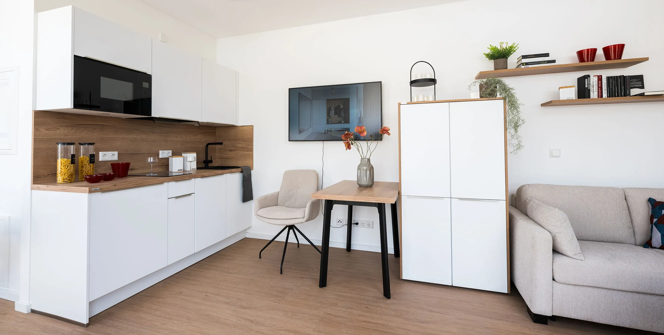 Einblick in eine eingerichtete Wohnung mit Küchenzeile, Schrank, kleinem Tisch und Fernseher. Foto: City-Press GmbH