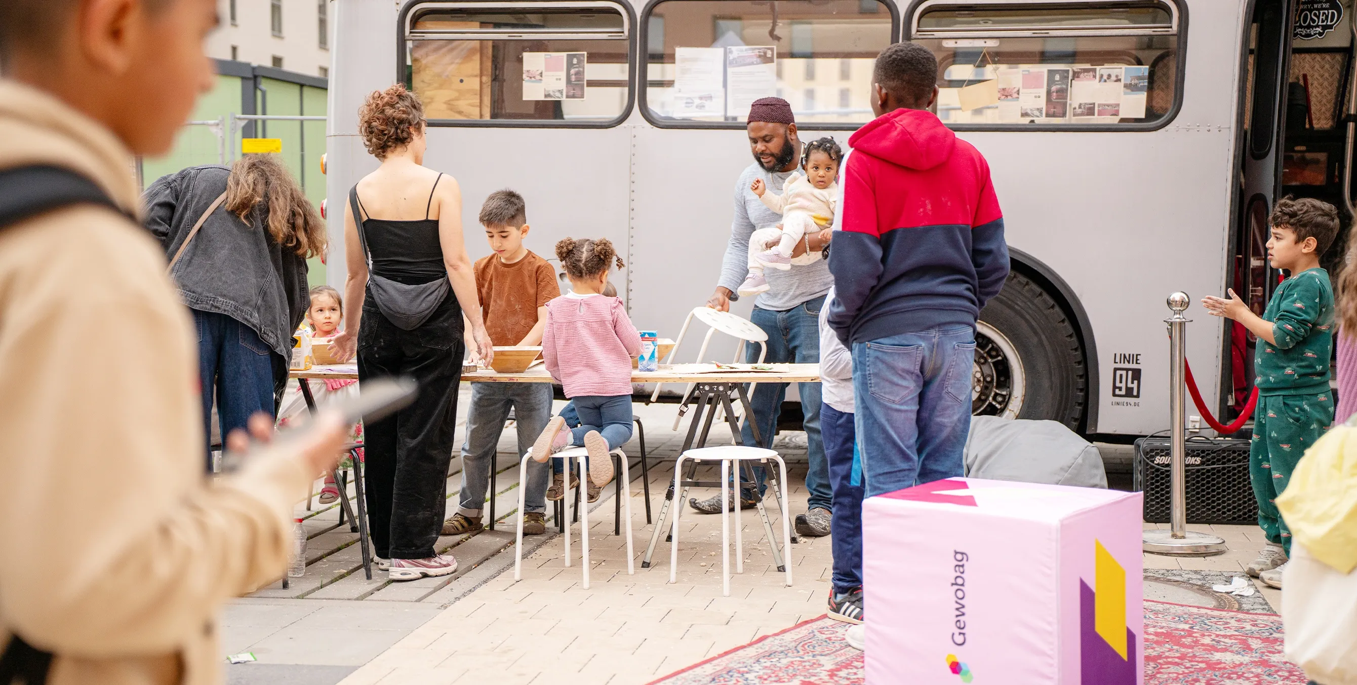 Aufnahme von einem Nachbarschaftsfest: Mehrere Menschen unterschiedlicher Ethnien vor einem Aktionsbus. Foto: Ralph Maak