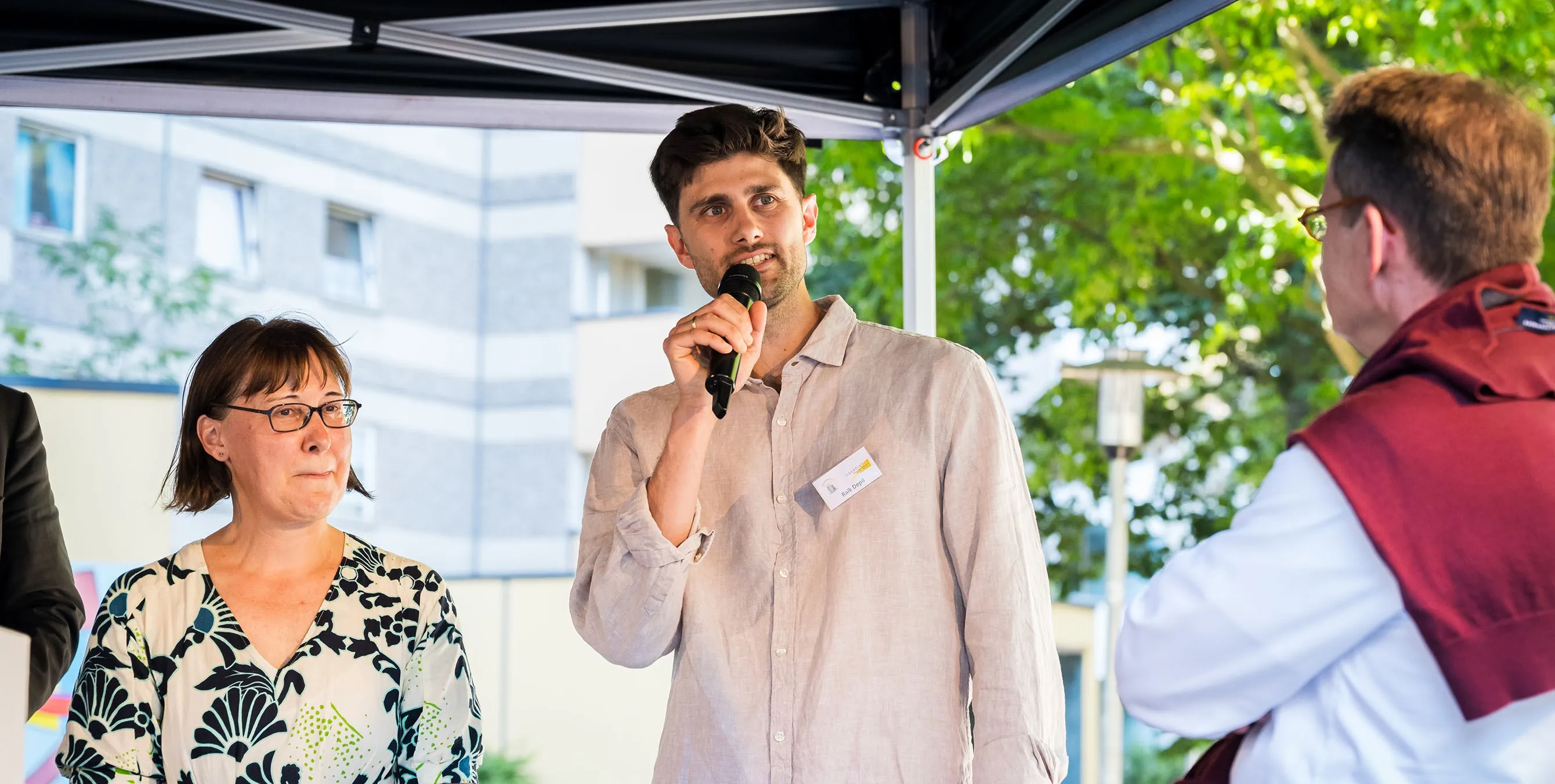 Ein junger Mann steht auf einer Bühne im Freien und spricht in ein Mikrofon. Foto: City-Press GmbH