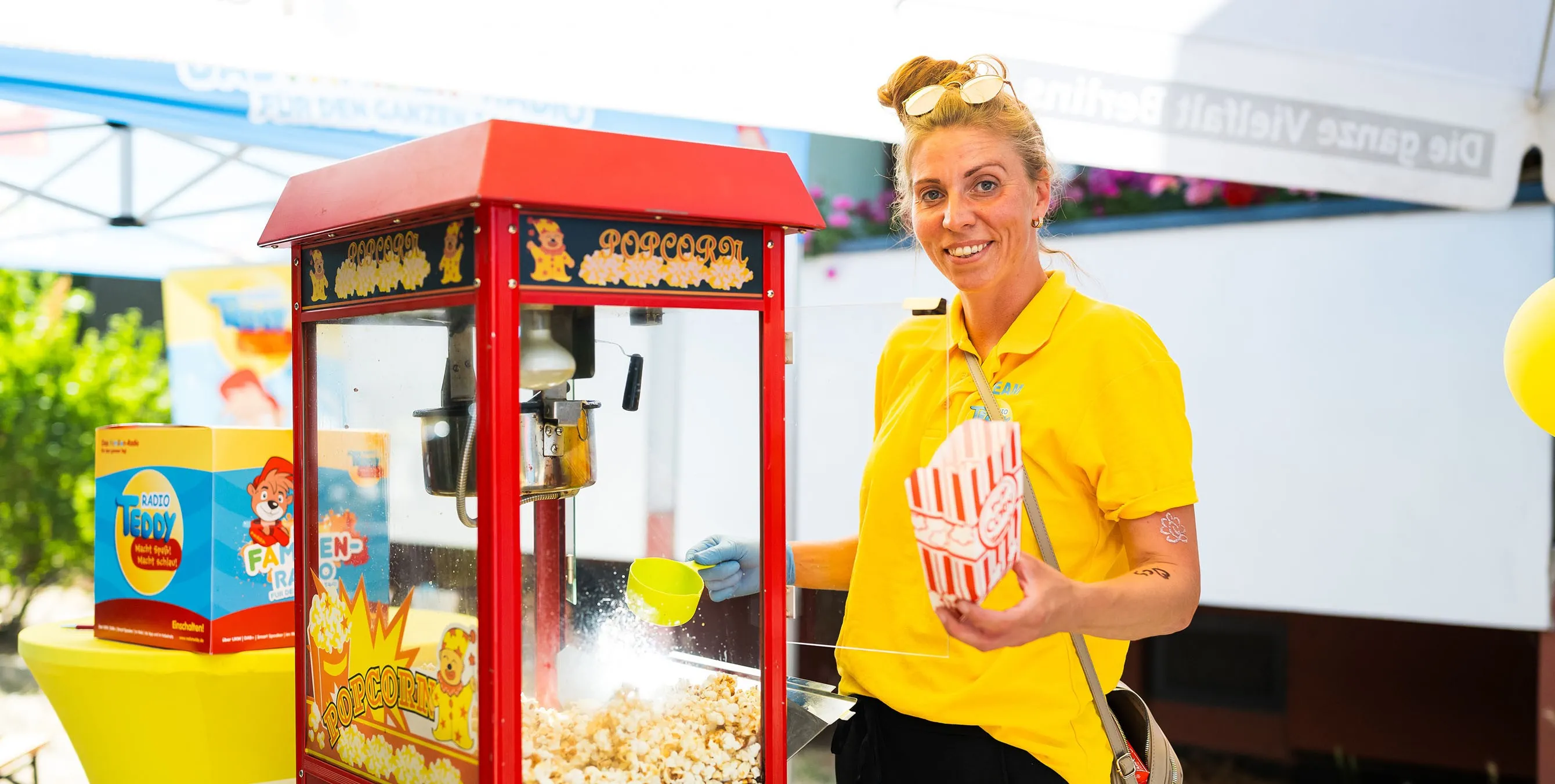 Eine Verkäuferin befüllt an einem Popcornstand eine Popcorntüte und lächelt in die Kamera. Foto: City-Press GmbH