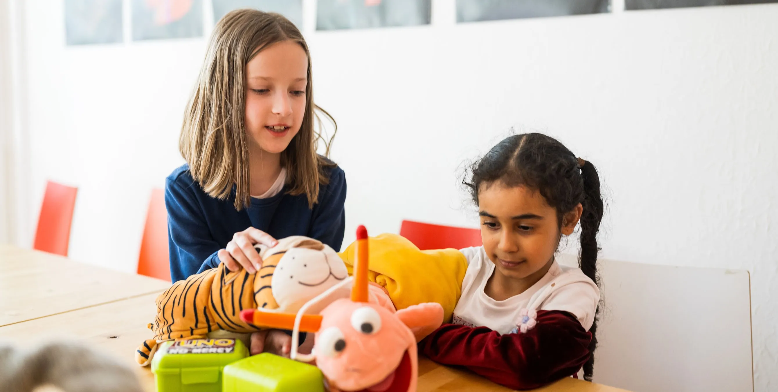 Zwei Mädchen spielen an einem Tisch mit Stoffpuppen. Foto: City-Press GmbH