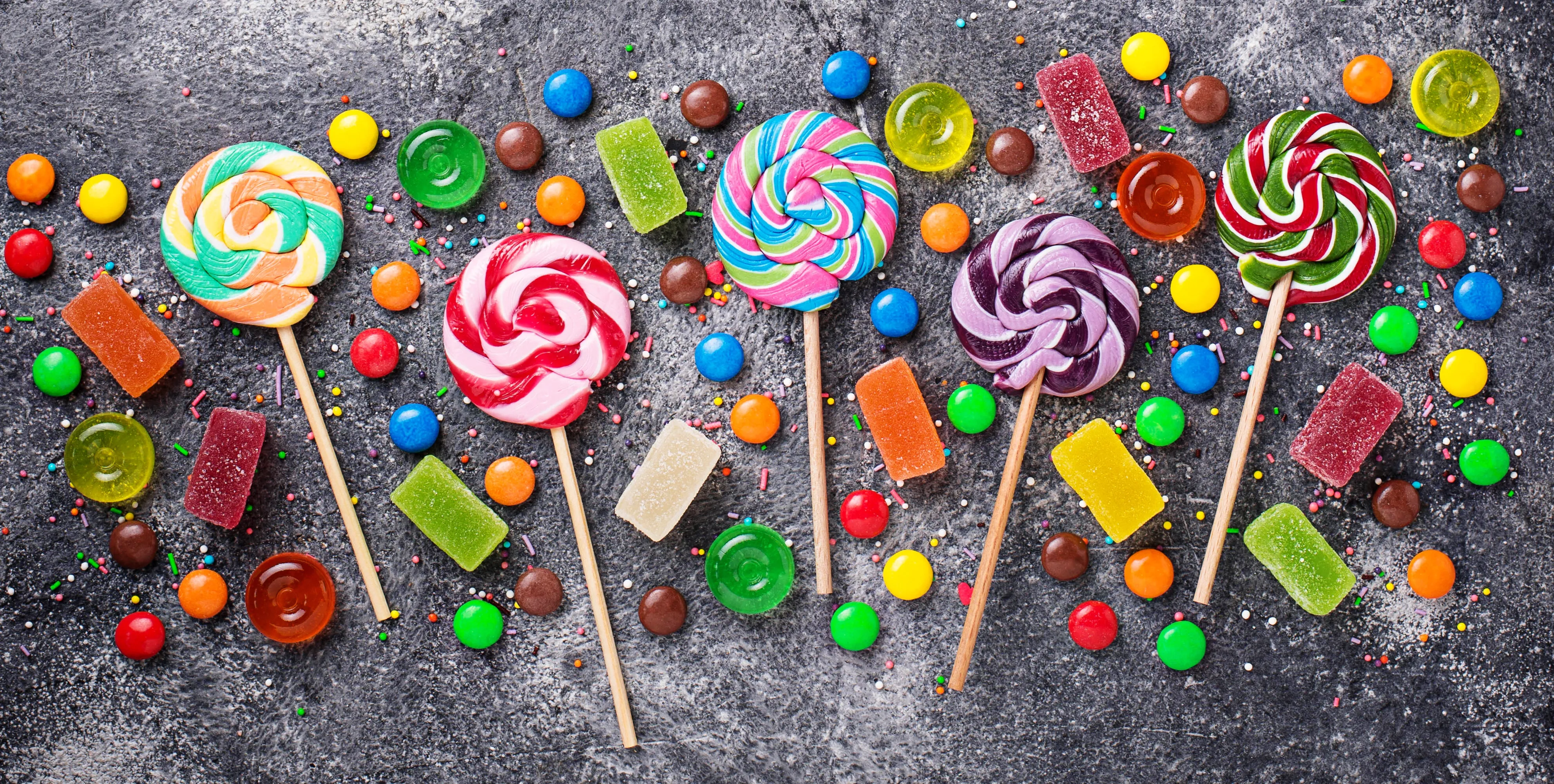 eine Sammlung bunter Süßigkeiten, darunter Bonbons und Lollis und Gummibärchen.