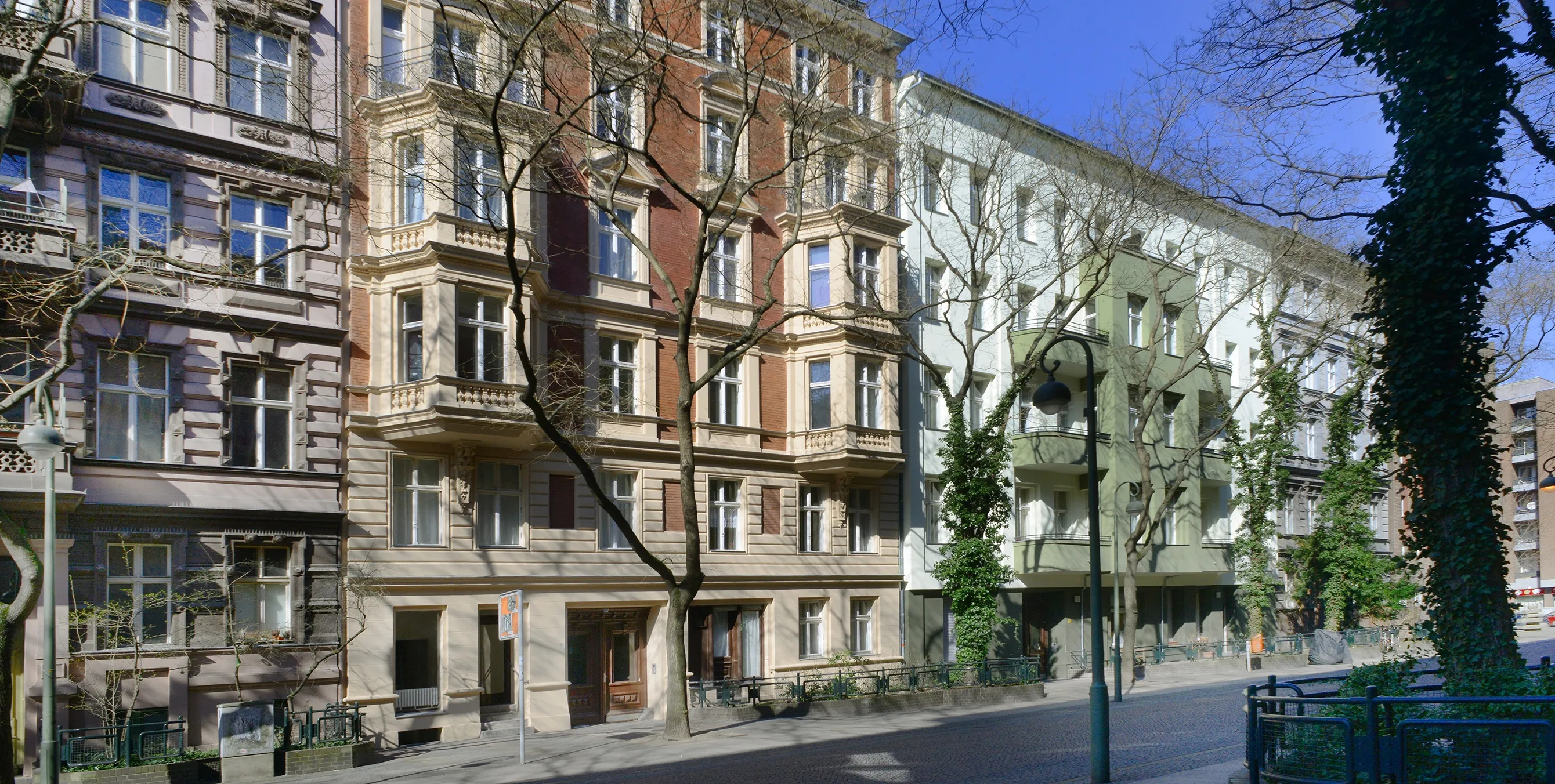 Blick auf eine Häuserzeile mit drei Gebäuden, darunter zwei sanierte Altbaufassaden. Foto: Gewobag