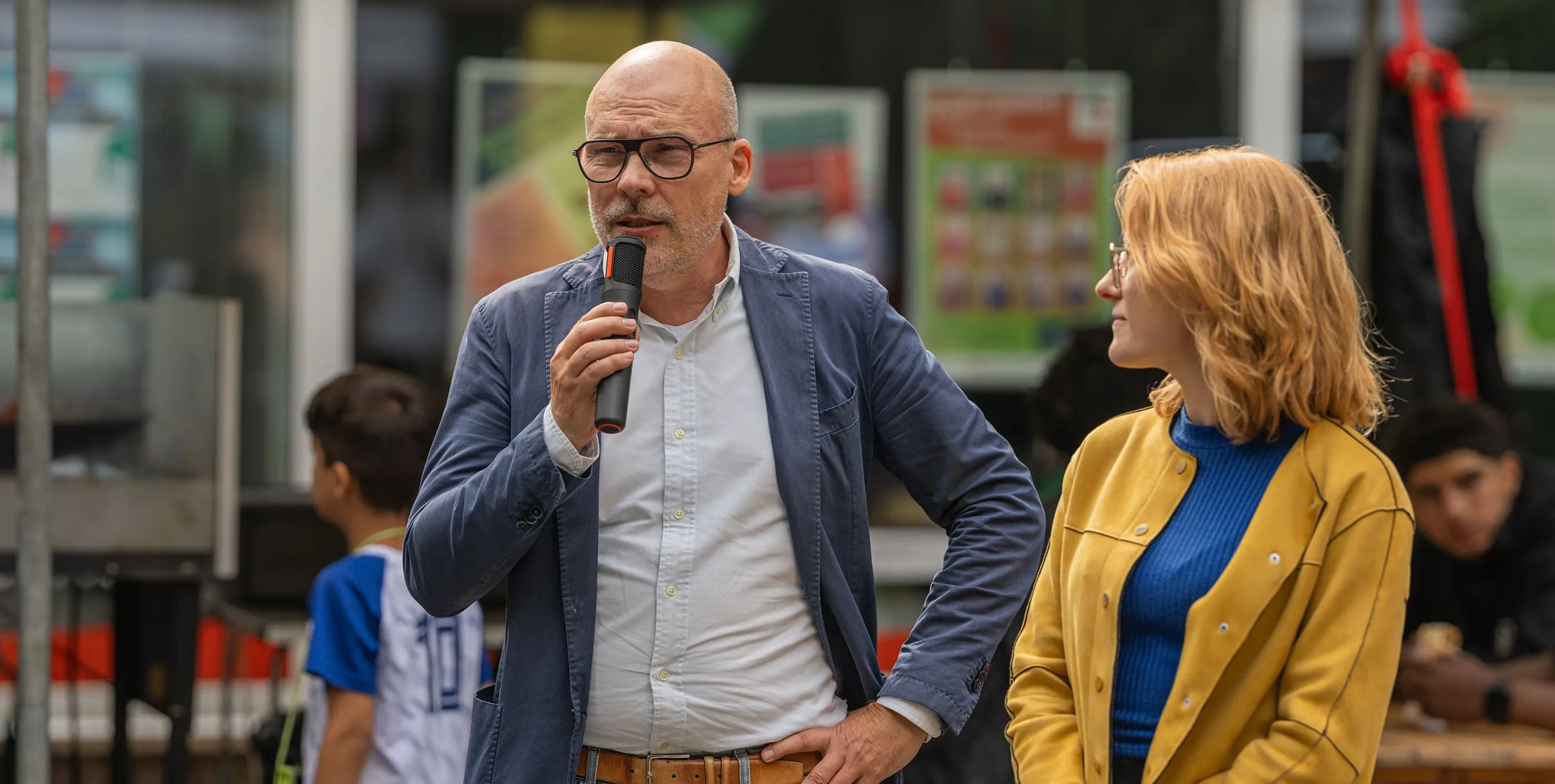 Ein Mann mit Brille steht im Freien und spricht in ein Mikrofon. Neben ihm steht eine junge Frau. Foto: Felix Seyfert