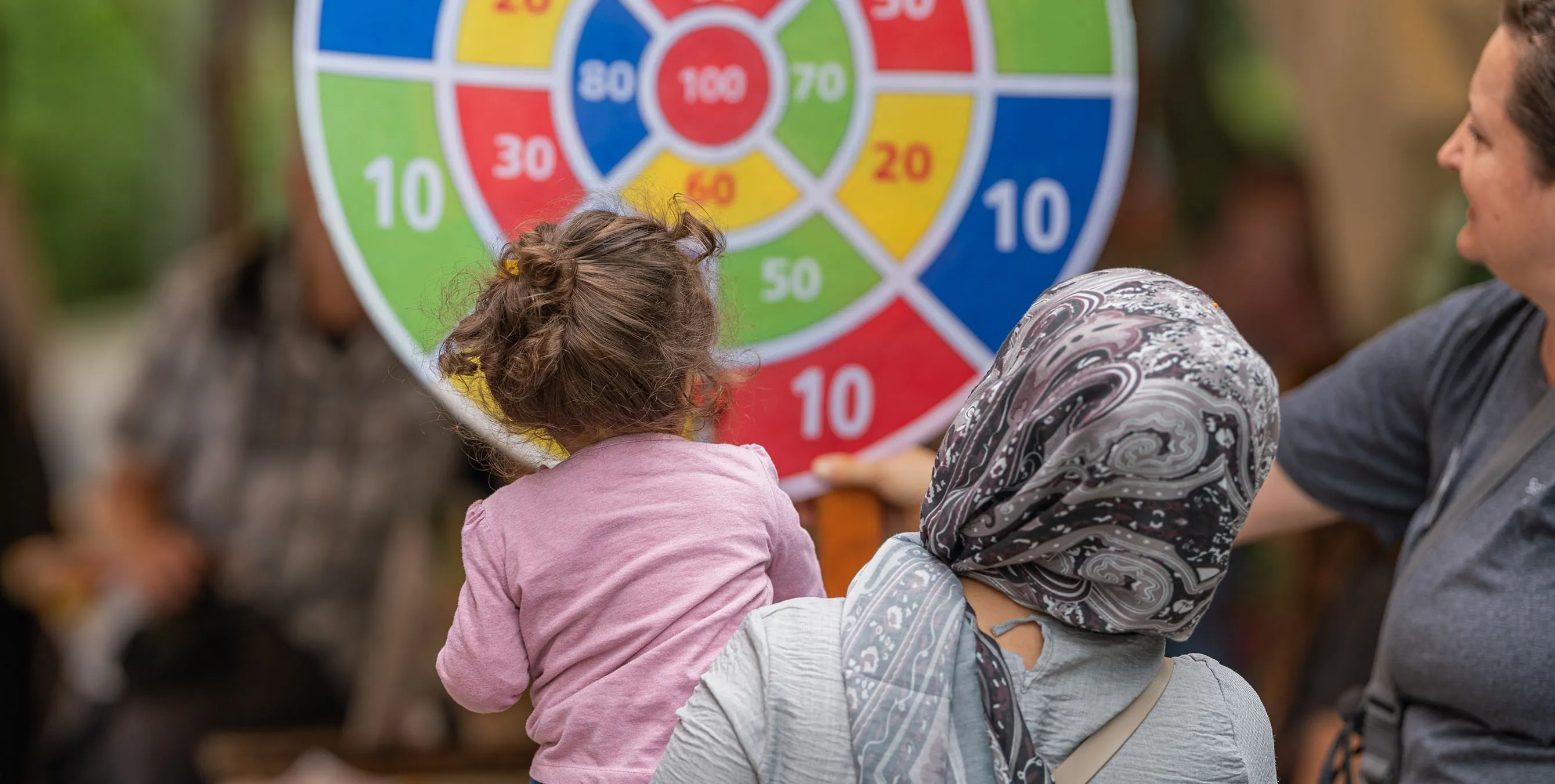 Szene von einem Quartierfest im Freien: Eine Familie an einem bunten Glücksrad. Foto: Felix Seyfert