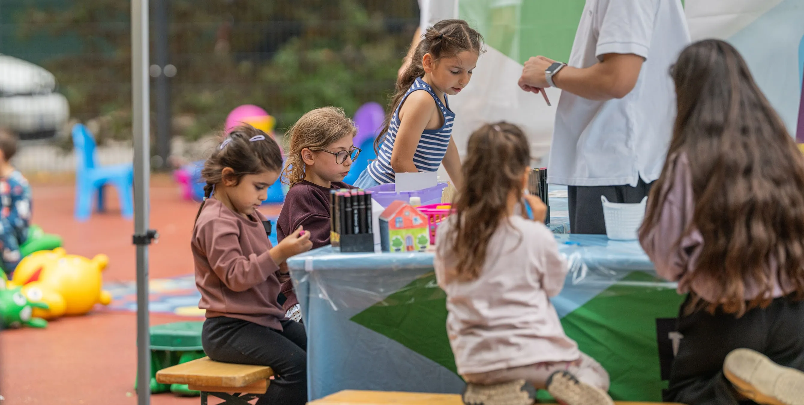 Szene von einem Quartiersfest im Freien: Fünf Kinder sitzen an einem Mal-Stand. Foto: Felix Seyfert