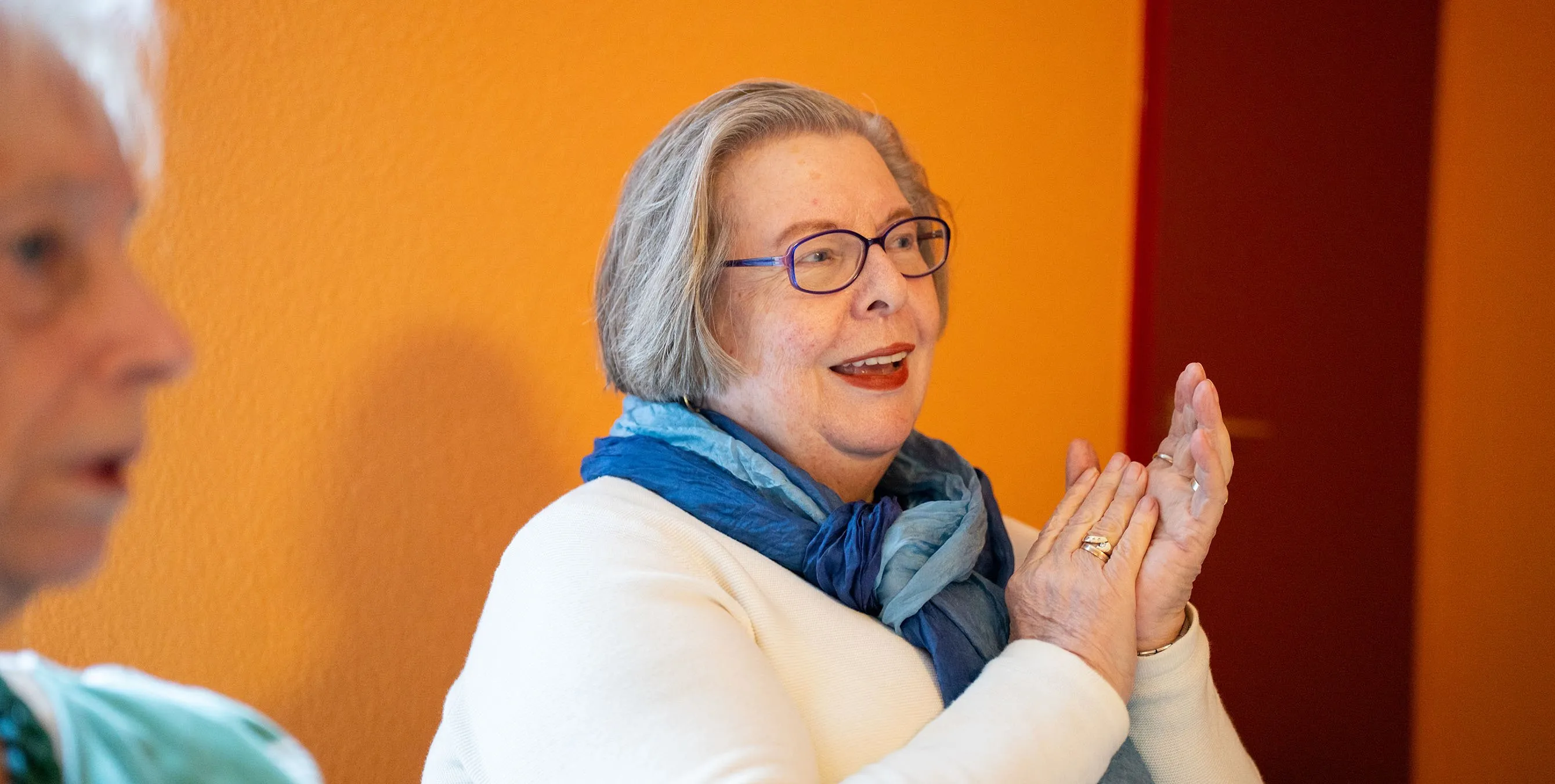 Eine Frau mit Brille schaut freundlich und klatscht in die Hände. Foto: Ralph Maak