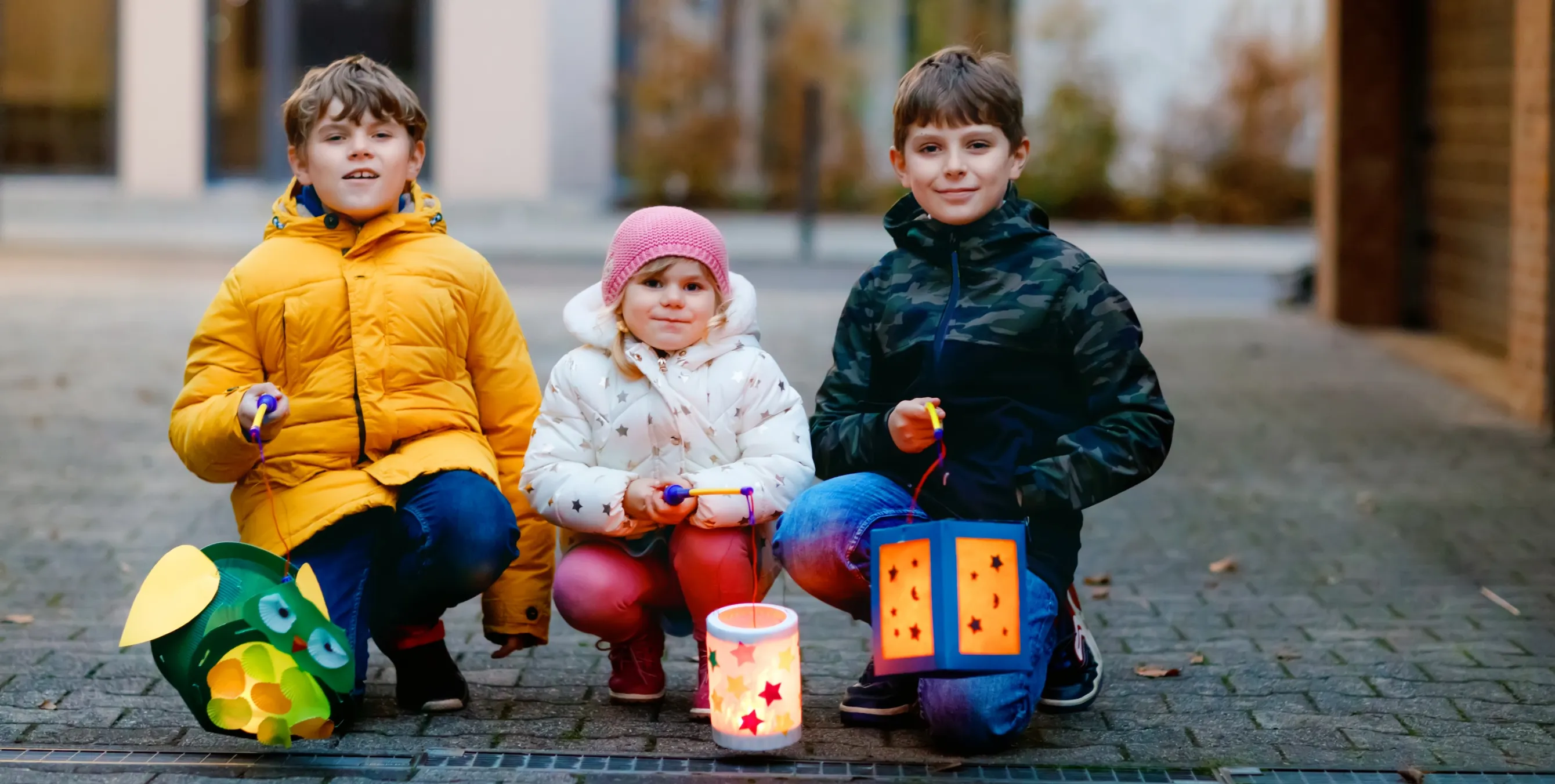 Drei Kinder mit Laternen auf der Straße