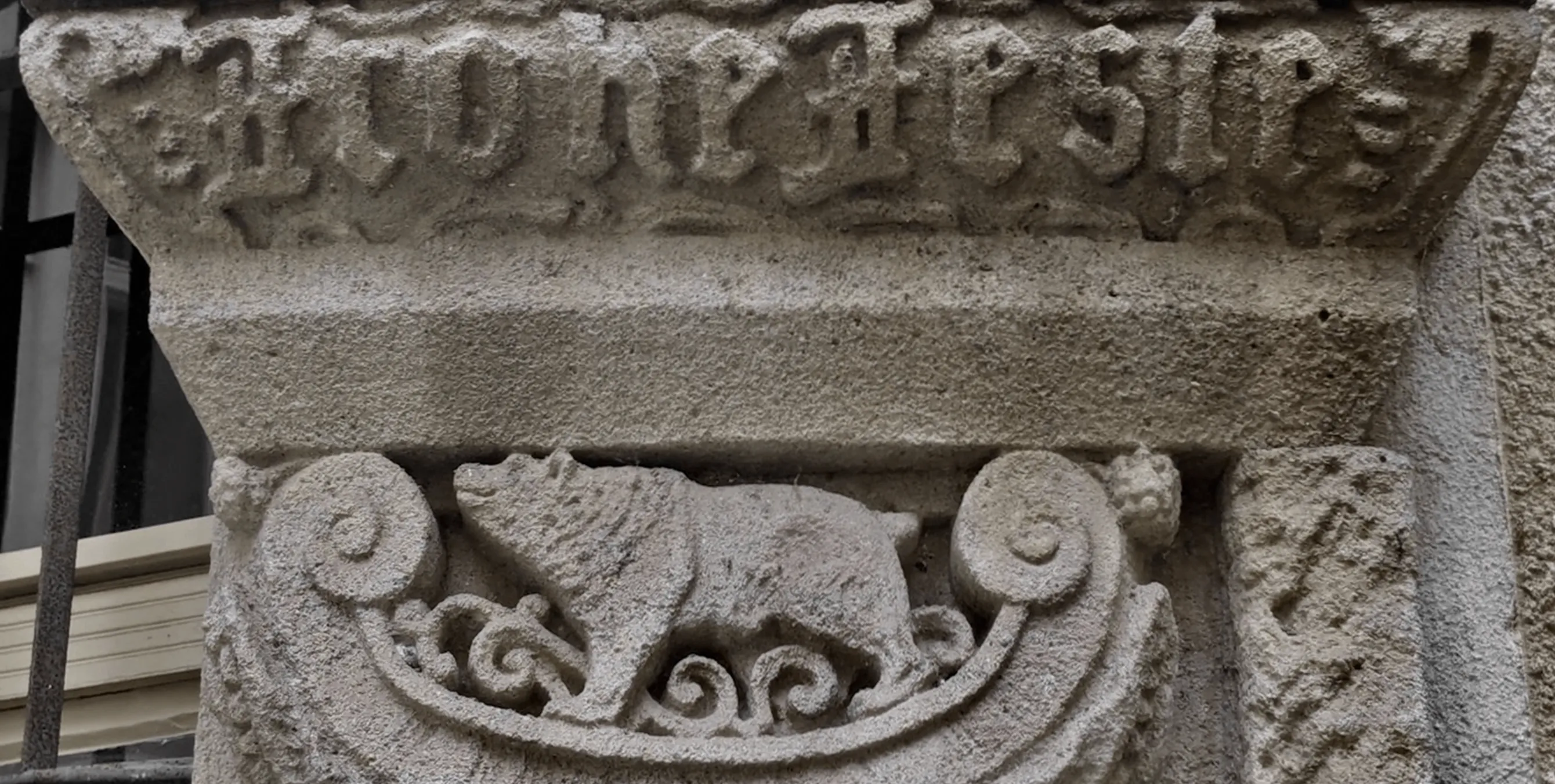 Detailaufnahme: ein Bären-Relief an einer Häuserwand, darüber der Schriftzug "Frohe Feste". Foto: Gewobag